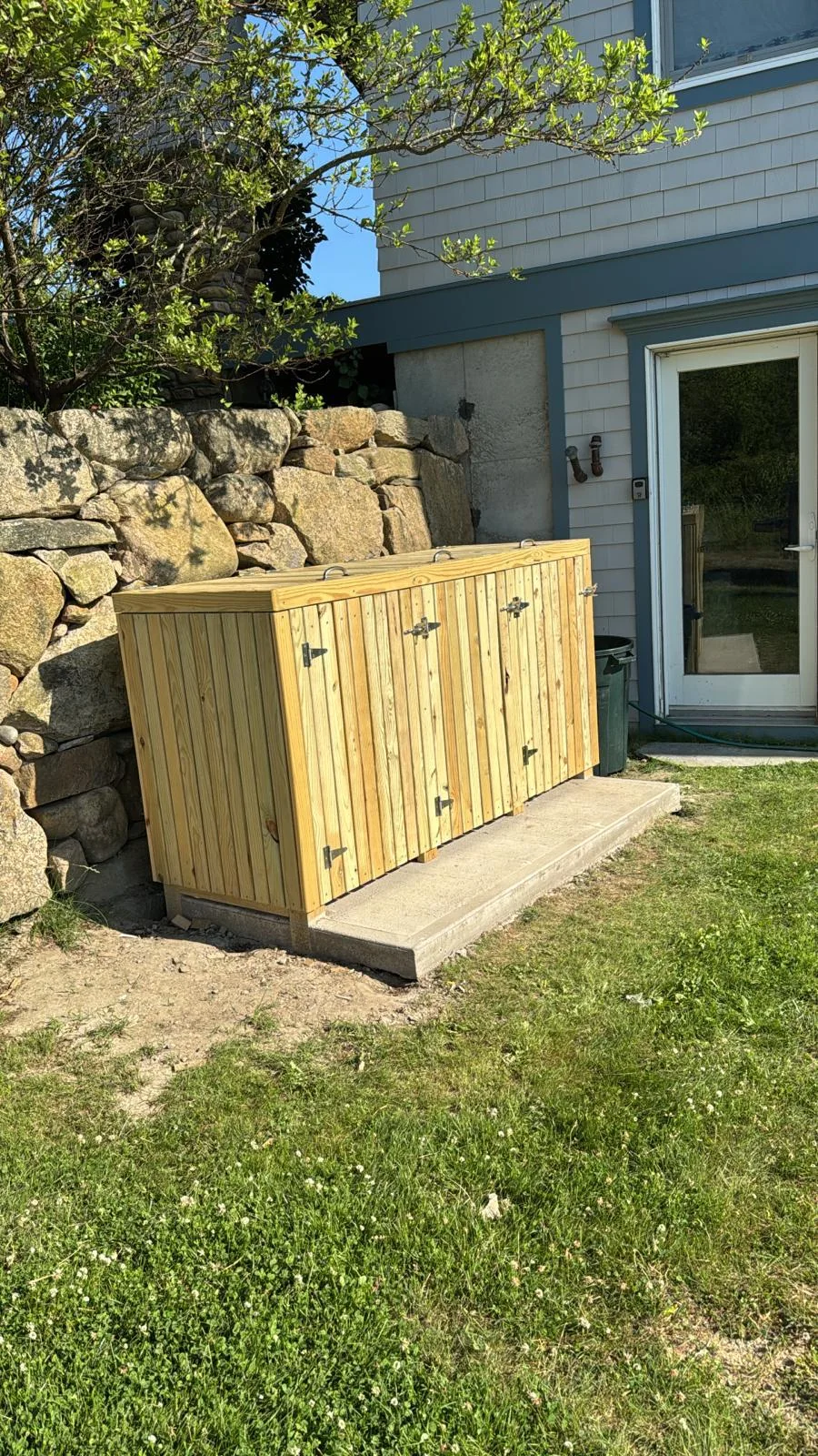 Custom cedar enclosure beside a stone wall